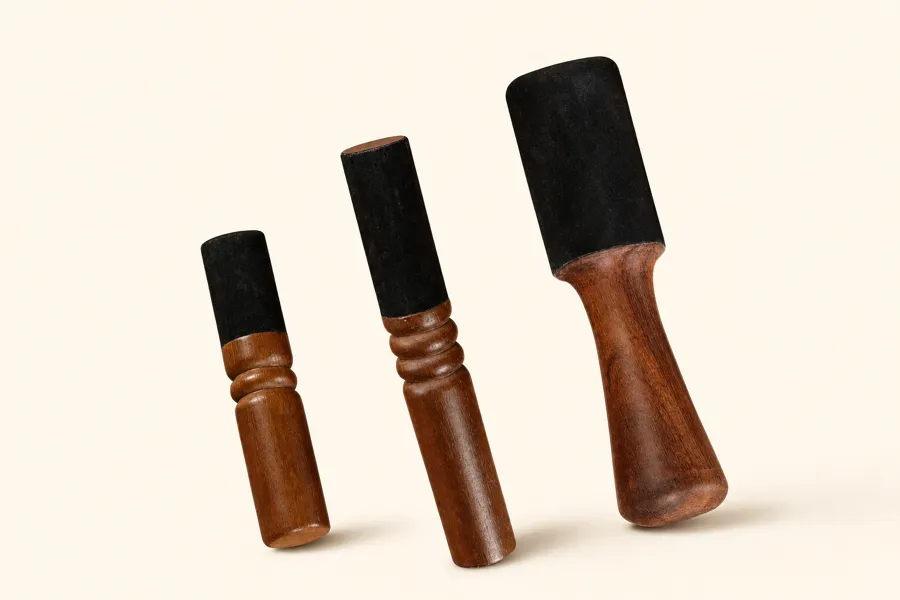Three leather-head singing bowl mallets lined up by size