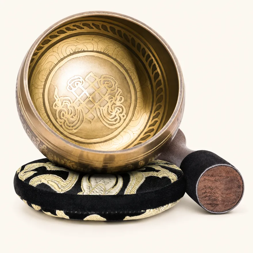 Singing bowl set with a traditional infinite-knot auspicious symbol engraved inside the bowl, on its silk cushion with the mallet