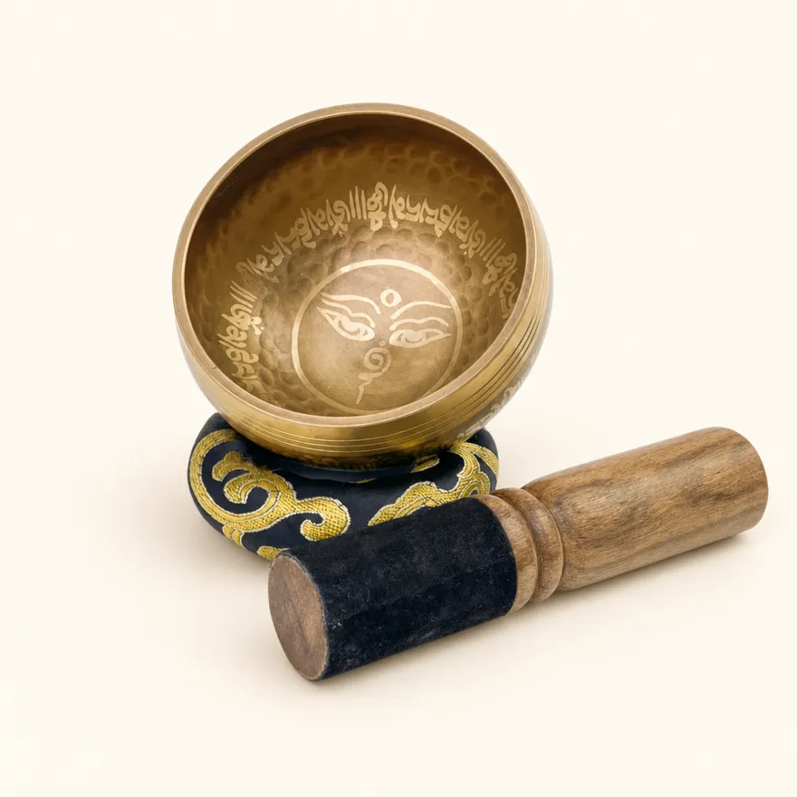 Singing bowl set with a golden stylized eye motif engraved inside the bowl, on its silk cushion with the mallet