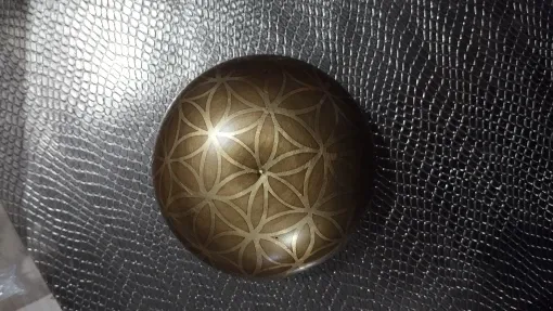 Verified buyer photo: Flower of Life pattern engraved across the base of the bowl, on a dark textured surface